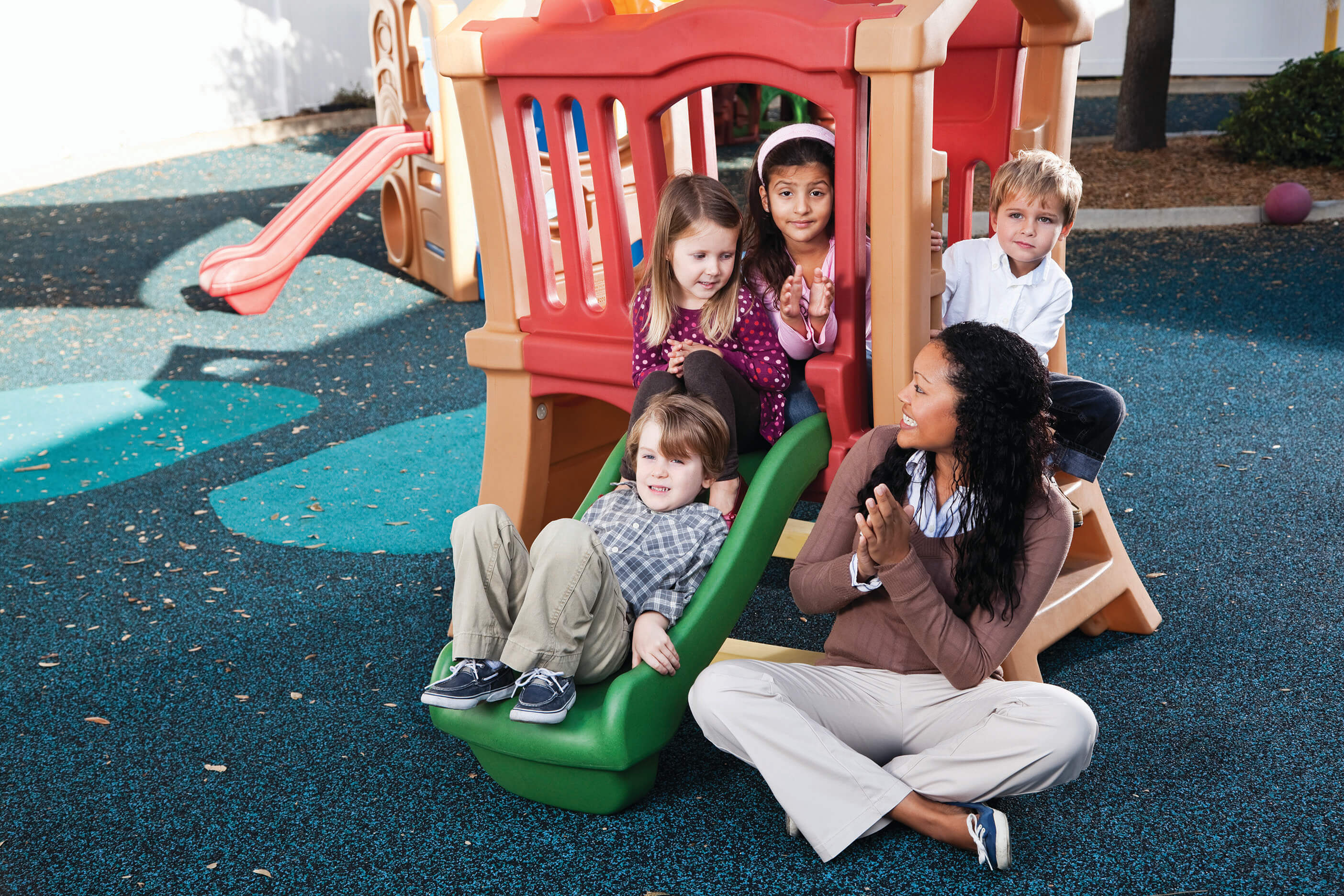 Four students and a teacher sitting on an outdoor play set